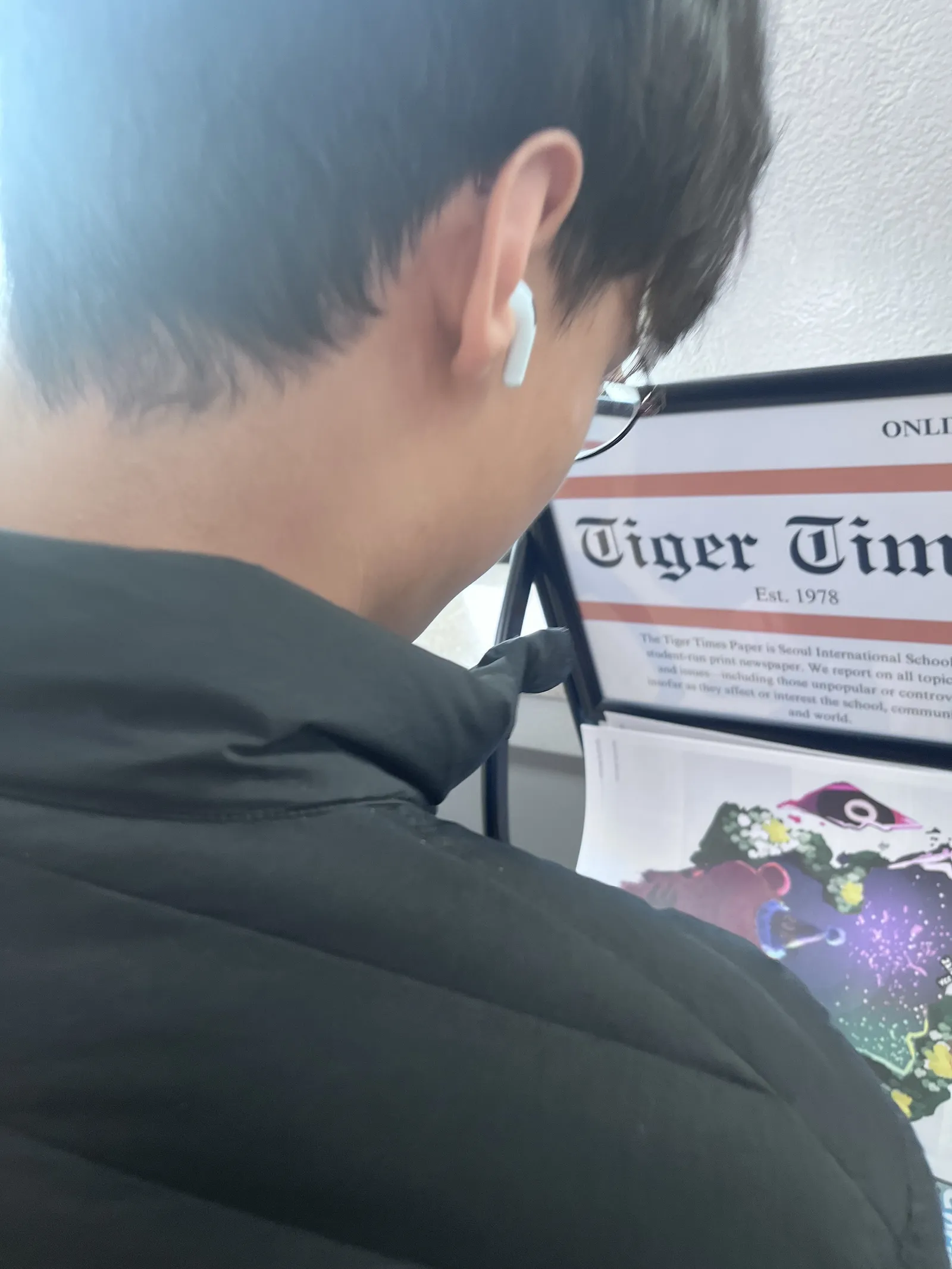 Student viewing the Tiger Times (Est. 1978) newspaper display rack at school